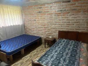 a room with two beds and a brick wall at Casa de Campo en Zuleta in Huamboya