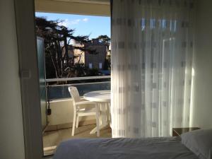 a bedroom with a bed and a balcony with a table at Résidence Le Crystal Dinard Plage in Dinard