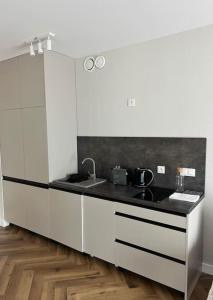 a kitchen with white cabinets and a black counter top at Revisit Szklarska B5 in Szklarska Poręba