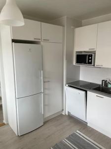 uma cozinha branca com armários brancos e um frigorífico em Kotimaailma - Valoisa kaksio Tikkurilan tuntumassa em Vantaa