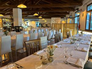 una sala da pranzo con tavoli lunghi e sedie bianche di Aquasole a Mercallo