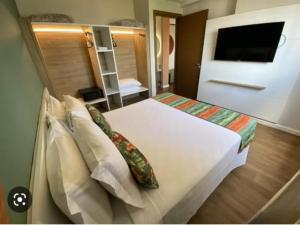 een slaapkamer met een groot wit bed met kussens bij HotBeachSuites Lazer e Diversão in Olímpia