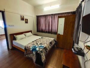 a bedroom with a bed and a telephone and a window at Cloud & Mist Inn, Kotagiri in Kotagiri