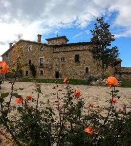 un vieux bâtiment en pierre avec des fleurs orange devant lui dans l'établissement Mas Postius, à Muntanyola
