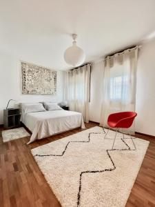 een slaapkamer met een bed en een rode stoel bij Crestudio Stanza accogliente vicino al Ponte Vecchio in Bassano del Grappa