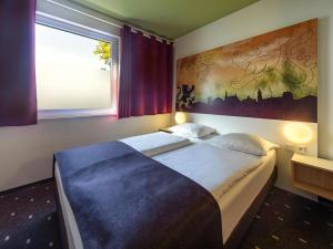 a bedroom with a large bed and a large window at B&B Hotel Weimar in Weimar