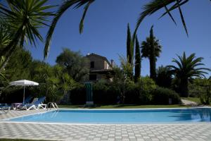 una piscina con palme e una casa sullo sfondo di Agriturismo Tenuta Sol Alto a Monsampolo del Tronto