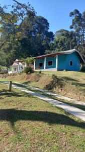 niebieski dom na wzgórzu z drogą w obiekcie Chalé doce beija-flor w mieście Campos do Jordão