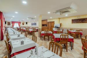un comedor con mesas blancas y sillas de madera en Hotel Restaurante Cazador en Pereiro