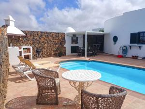 een patio met een tafel en stoelen naast een zwembad bij Casa Oasis in Teguise