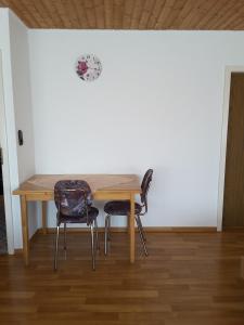una mesa de madera con 2 sillas y un reloj en la pared en Haus Hopp - Bungalow, en Dahme