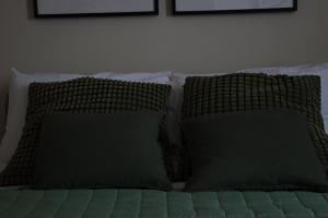 a bed with two pillows and two green pillows at B&B La Casetta in Cambiago