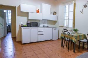 フィレンツェにあるコルテ パッシ フローレンスの白いキャビネット、テーブルと椅子付きのキッチンが備わります。