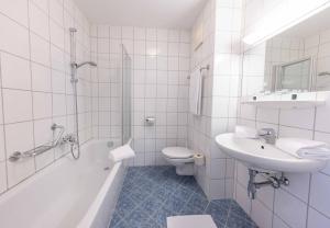 a white bathroom with a sink and a toilet and a tub at Gästehaus Rudolfo in Zell am See