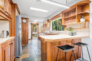 a kitchen with wooden cabinets and a counter and stools at Hampton Vintage Soul with Pool in Melbourne