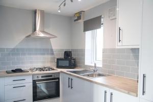 a kitchen with white cabinets and a sink and a stove at White Rose Cottages, Near Thirsk in Thirsk