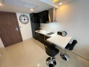 a kitchen with a white counter and black chairs at Large Deluxe Condo 5 Grand Avenue Central Pattaya in Pattaya Central +25 photos