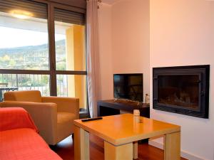 sala de estar con sofá, TV y mesa en Apartamentos Las Margas Sabiñánigo 3000, en Sabiñánigo