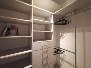 a walk in closet with white shelves and a glass shower at Apartamenty Tychy Kopernika in Tychy