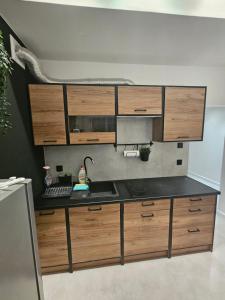 a kitchen with wooden cabinets and a black counter top at Apartament Panorama Miasta in Gdynia