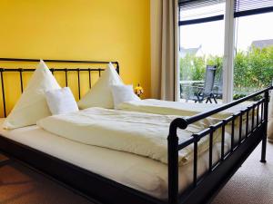 2 Betten mit weißen Kissen in einem Zimmer mit Fenster in der Unterkunft Villa Sonnenterrasse in Pelzerhaken