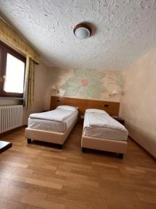 Hotel Breuil في بيريول تشيرفينيا: سريرين في غرفة مع وردة مرسومة على السقف