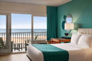 a bedroom with a bed and a balcony with the ocean at Howard Johnson by Wyndham Ocean City Oceanfront in Ocean City