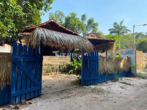 een huis met een blauwe poort en een rieten dak bij Redario BOTOS DE ALTER in Alter do Chao