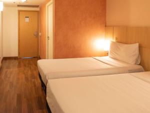 una camera d'albergo con due letti e una porta di ibis Sao Paulo Barra Funda a San Paolo
