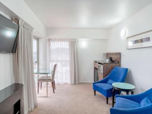 a room with blue chairs and a table and a desk at Mercure Wellington Central City Hotel and Apartments in Wellington