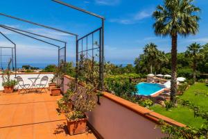 a balcony with a swimming pool and palm trees at Villa Donnafugata in Santa Domenica