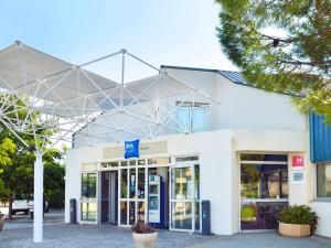a white building with a blue sign in front of it at ibis budget Aubagne Paluds Agora in Aubagne