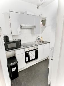 a white kitchen with a sink and a microwave at Aroluchi Ville - Cosy Studio 