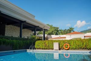 a swimming pool in front of a building with a hedge at Hilton San Salvador in San Salvador