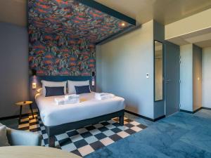 ein Schlafzimmer mit einem großen Bett und einem Gemälde an der Wand in der Unterkunft ibis Styles Dijon Sud Domaine De Beauregard 21600 Longvic in Dijon