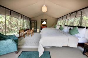 Talek的住宿－Olkinyei Mara Tented Camp，卧室配有一张床和一张桌子及椅子