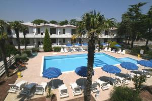 una piscina del complejo con sillas, sombrillas y una palmera en VILLAGGIO LIDO - Cavallino, en Cavallino-Treporti