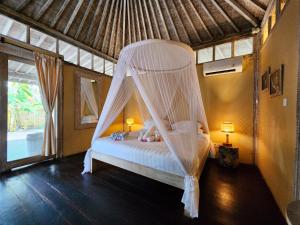 a bedroom with a bed with a mosquito net at Bamboo Lodge in Gili Trawangan