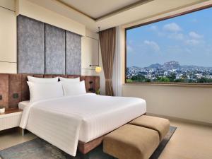 a bedroom with a large bed and a large window at Novotel Jodhpur ITI Circle in Jodhpur