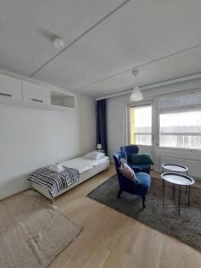a living room with a bed and a blue chair at Kotimaailma - Avara ja valoisa studio Vantaalla in Vantaa