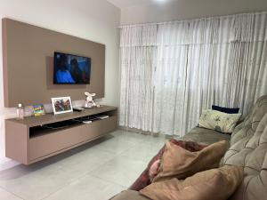 ein Wohnzimmer mit einem TV und einem Sofa in der Unterkunft Casa com piscina em Itapema próximo a praia in Itapema