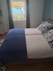um quarto com uma cama com um cobertor azul e uma janela em Haus am Schloss em Bleiburg