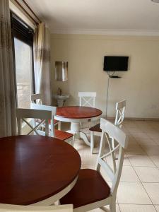 salon z dwoma stołami i krzesłami oraz telewizorem w obiekcie Twinkle Blue Inn w mieście Namugongo