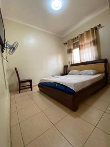 a bedroom with a bed and a chair in it at Twinkle Blue Inn in Namugongo