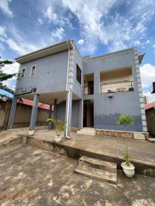 a house with two potted trees in front of it at Twinkle Blue Inn in Namugongo