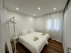 Un dormitorio con una cama blanca con dos sombreros. en Apto reformado a 20 mins de la playa en Pasajes Ancho