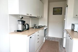 a small kitchen with white cabinets and a sink at Havi Apartment in Riihimäki