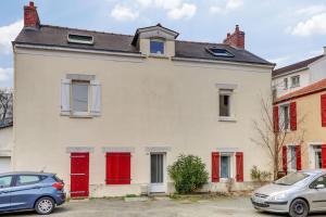 una casa bianca con porte rosse e auto parcheggiate di fronte di Le Globe Nantais a Nantes