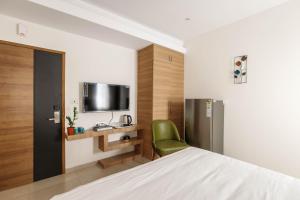 a bedroom with a bed and a tv and a chair at SpringPetals Serviced Apartments in Bangalore