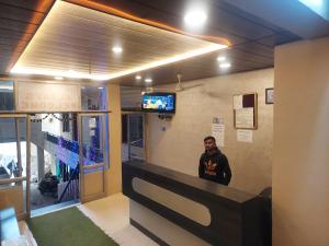 a man sitting at a counter in a restaurant at Hotel Always Welcome by SAH in Mount Ābu